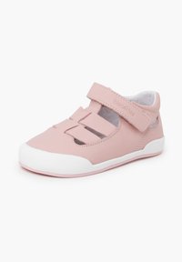 Zapatos de cuero rosa con una correa de velcro, diseño perforado y suela de goma blanca. Forma redondeada, ligeros y texturizados para mejorar el agarre.