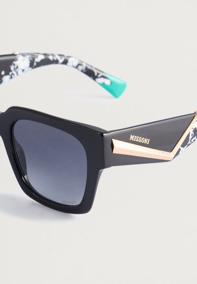 Czarne okulary przeciwsłoneczne w dużym rozmiarze z błyszczącym wykończeniem, z złotym akcentem i wzorzystą czarnobiałą zausznikiem z miętowym zielonym końcem.