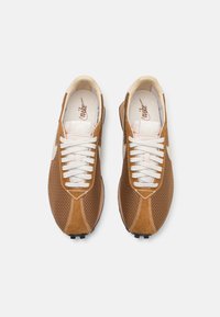Chaussures de sport en suède brun et en mesh avec des lacets blancs, des coutures contrastées et des crampons en caoutchouc. Design classique avec une silhouette courbée.