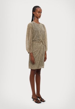 Beez dress, mille leopardi mustridega, puffitud varrukatega ja sõlme detailiga vööl; koos mustade rihmadega sandaalidega.