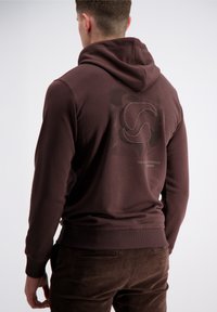 Bordeauxfarbener Kapuzenpulli mit einer strukturierten Grafik auf dem Rücken, die ein kreisförmiges Logo zeigt. Aus einem glatten Stoff gefertigt, mit einer Kängurutasche und gerippten Bündchen.