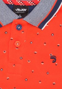 Rode poloshirt van een textuurachtige gebreide stof, met een blauwe en witte patroonkleur, geborduurd logo en decoratieve kleine geometrische ontwerpen.