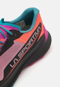 Sportskor med färgschemat svart, rosa, orange och teal. Ovandel i mesh med logotyp, vadderad krage och strukturerad gummisula.