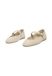 Zapatos planos de tejido beige con puntera afilada y tira en el tobillo, que presentan una suela suave y un diseño de superficie texturizada.