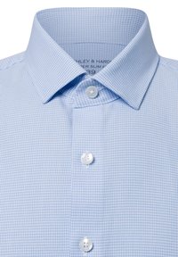 Hellblau kariertes Hemd mit Button-down-Kragen und drei weißen Knöpfen; der Stoff hat eine strukturierte, gitterartige Musterung.