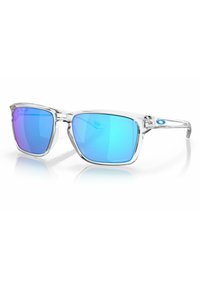 Gafas de sol rectangulares con montura de plástico transparente y lentes degradados azules, con un borde curvado en la parte frontal y un detalle de marca en el lateral.