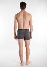 Boxer briefs in navy with a geometric pattern, featuring a solid waistband. Material appears smooth with a fitted design, shown from the back.