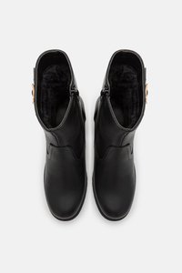 Bottes noires à cheville avec un extérieur en cuir, doublure intérieure douce, fermetures éclair latérales et un design incurvé. Accentuées de détails en métal doré.