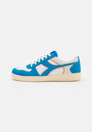Zapatilla azul y blanca con materiales de ante y cuero. Presenta una puntera perforada, acentos en naranja y una suela de goma crema.