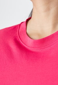 Roze katoenen t-shirt met ronde hals. Gladde textuur en nauwsluitend ontwerp, met een versterkte kraagnaad.