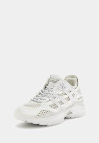Baskets blanches de sport avec des panneaux en mesh, des accents en synthétique texturé et une semelle extérieure translucide. Comprend un laçage proéminent et un détail de logo.
