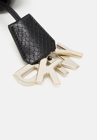 Portachiavi in pelle nera con superficie texturizzata e una targhetta in metallo dorato che riporta le lettere "D", "K" e "Y".