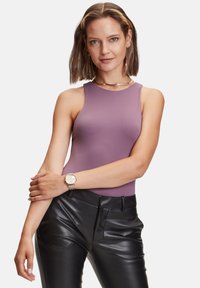 Mouwloze lavendelkleurige bodysuit met een ronde halslijn, gecombineerd met strakke zwarte leren broeken. Een zilveren horloge om de pols voegt een metallic detail toe.