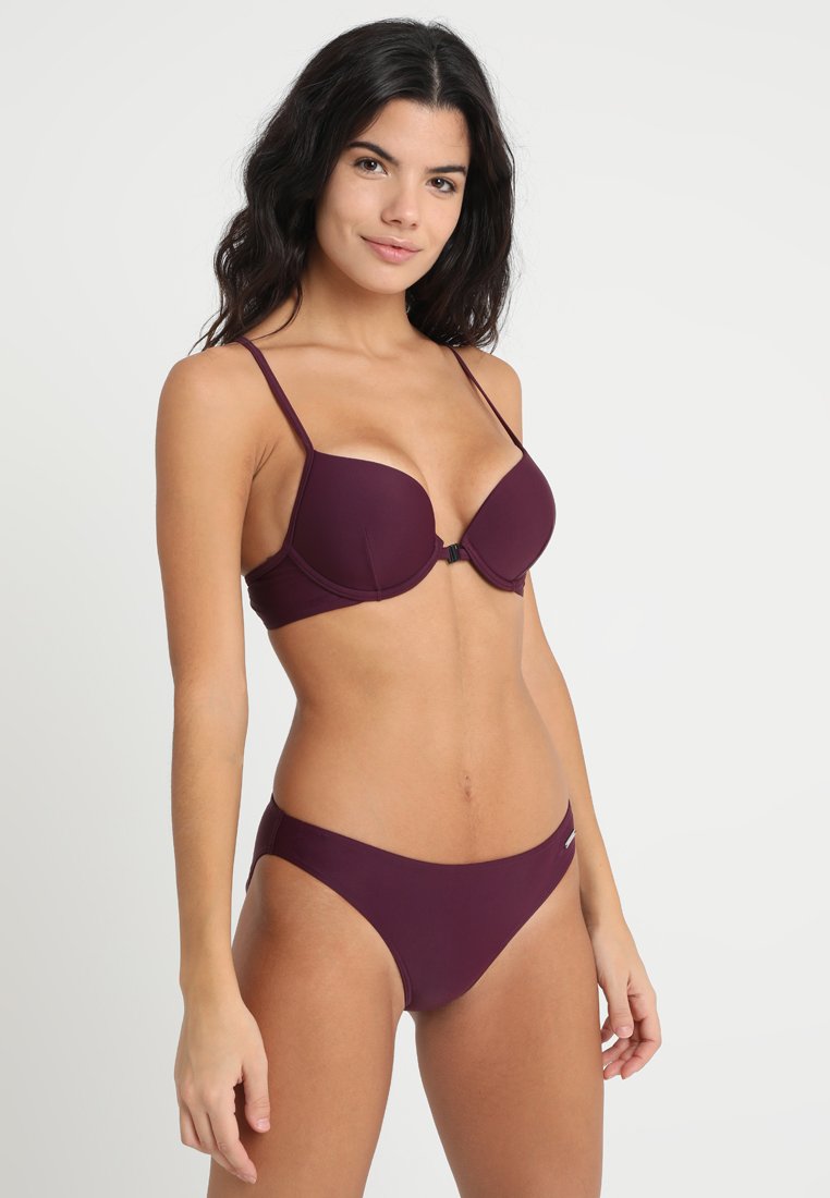 Burgunderfarbene Bikiniset mit einem gepolsterten BH mit verstellbaren Trägern und Hakenverschluss, kombiniert mit tief sitzenden Bikini-Unterteilen. Glatte Textur.