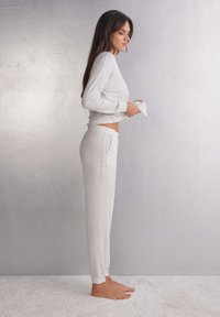 Lichtgrijze geribbelde loungewear set met een lange mouw top met een ronde zoom en bijpassende taps toelopende broek met zijzakken.
