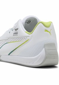 Weiße Sportschuhe mit grünen Akzenten, strukturierten Seiten und glatter Oberfläche. Mit gepolstertem Fersenbereich und perforierten Details für Atmungsaktivität.