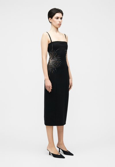 Fekete midi ruha testhez simuló szabással, vékony pántokkal, és oldalt fémes színű tűzijátékra emlékeztető díszítésekkel.