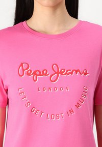 Rosa bomull t-shirt med rundad halsringning. Framtrycket i vitt och rött läser "Pepe Jeans London" och "Låt oss gå vilse i musiken."