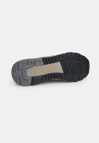Black rubber shoe sole with textured tread for grip, featuring a grey midsole and the word "FLEXIBLE" in orange on a light panel.