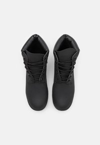 Black ankle boots with a smooth leather upper, rounded toe, and lace-up design. Cushioned collar for comfort and flexibility.