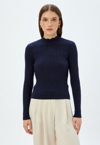 Marineblaues, geripptes Langarmshirt mit hohem Kragen, das einen gewellten Saum und eine taillierte Silhouette aufweist. Glatte Textur, minimalistisches Design.