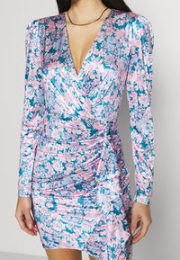 Floral wrap dress in blue, pink, and white, featuring long sleeves, a deep V-neck, and gathered side detailing for a fitted silhouette.