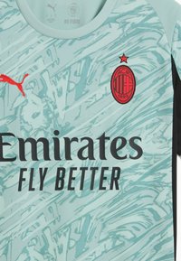 Vaaleansininen urheilu paita abstraktilla kuviolla, mustat lyhyet hihat, punainen Puma-logo, ja musta "Emirates Fly Better" -teksti mustan ja punaisen joukkueen logon alla.