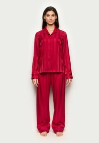 Rotes Satin-Pyjama-Set mit einem langärmeligen Hemd mit Knopfleiste und gestreifter Textur, kombiniert mit einer passenden, locker sitzenden Hose.