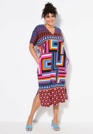 Vestido de cuello en V con llamativos patrones geométricos en rosa, negro, naranja y azul. Manga corta, aberturas laterales y un detalle de dobladillo con volantes.