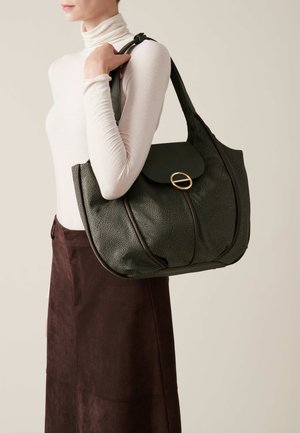 Large green handbag with a pebble texture, rounded shape, gold hardware, and a flap with a circular closure. Worn on the shoulder.