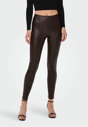 Brune faux læder leggings med høj talje, der har en glat overflade og sømdetaljer, parret med sorte strop hæle.