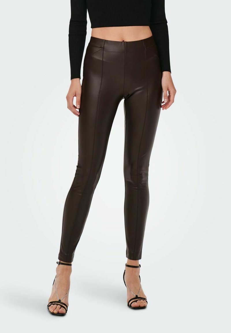 Bruna fusk läder leggings med hög midja, som har en slät yta och sömdetaljer, i kombination med svarta sandaletter med remmar.