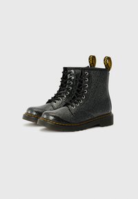 Botas de tobillo negras de purpurina con cordones, punta redondeada, suela de goma, bucles para el talón amarillos y detalle de costura en contraste.