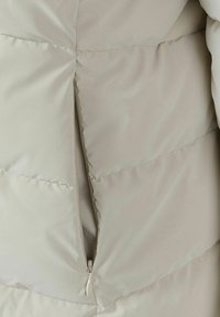 Sezione di una giacca imbottita grigia chiaro con cerniera visibile e motivo cucito. Texture liscia e gonfia; nessun altro dettaglio notevole.