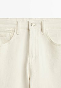 Jeans en denim blanc avec une coupe classique à cinq poches, dotés d'une fermeture à bouton en métal et de jambes droites, texture lisse et légèrement texturée.