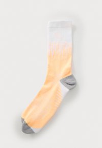 Light orange and white socks with a gradient design; gray heel and toe accents; textured fabric with diagonal stripes and patterns.