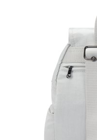 Mochila de tela gris claro con un bolsillo lateral con cremallera, correa ajustable y fondo plano. Presenta una textura suave y un diseño discreto.