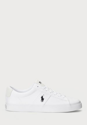 Baskets basses blanches avec lacets, un logo joueur de polo noir sur le côté et une semelle en caoutchouc propre.