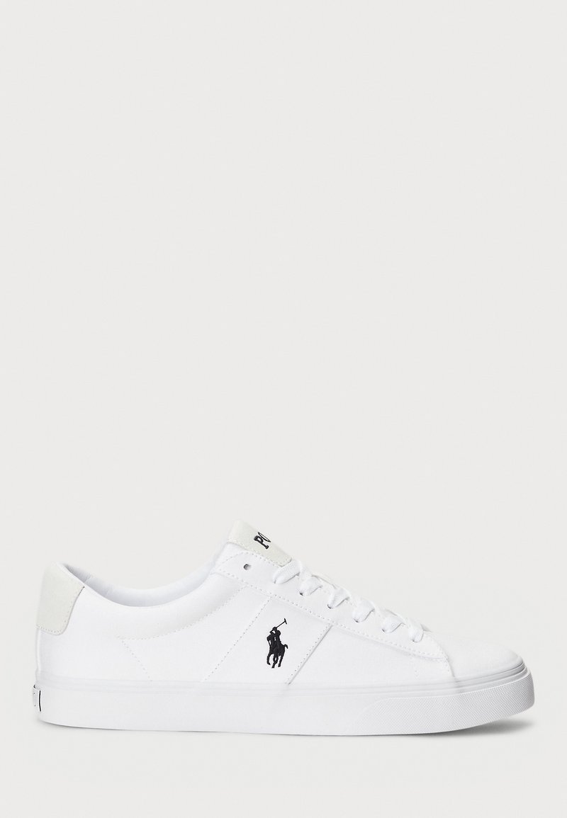 Baskets basses blanches avec lacets, un logo joueur de polo noir sur le côté et une semelle en caoutchouc propre.