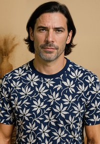 Navyblauwe t-shirt met korte mouwen, versierd met witte bloemenpatronen en zwarte centra. Gemaakt van zachte stof met een ronde hals.