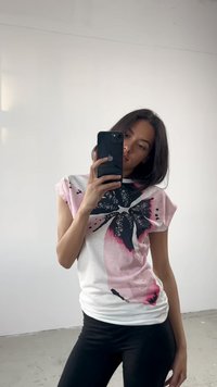 Witte korte mouwen t-shirt met een roze en zwarte vlinderontwerp, met een gladde textuur en een losse pasvorm, gedragen met zwarte leggings.