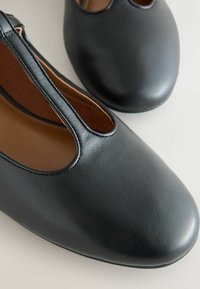 Černé kožené mokasíny s kulatou špičkou a středním výřezem, zobrazené z blízkého horního pohledu.