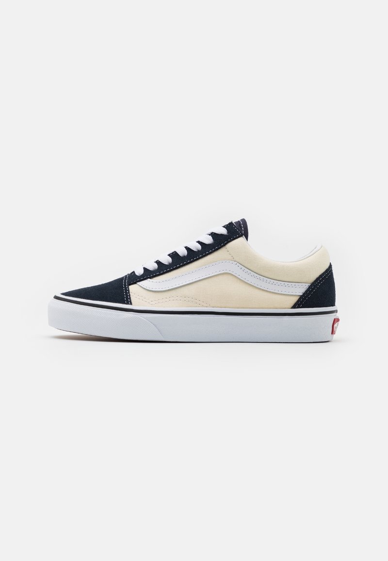 Baskets basses en daim marine et toile crème, avec des accents en cuir blanc, des lacets ronds et une semelle en caoutchouc blanc avec une bande noire.