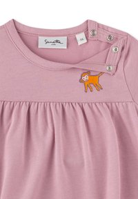 Rosa Baumwollbluse mit Raffun̈gdesign, rundem Ausschnitt und Druckknopfverschlüssen. Auffälliger gestickter oranger Löwe auf der Brust. Größenetikett sichtbar.