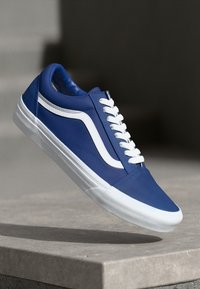 Blauer Sneaker mit weißen Akzenten, niedrig geschnittenes Design, oberer Teil aus glattem Kunstleder, runde Zehenpartie und strukturierte weiße Gummisohle.