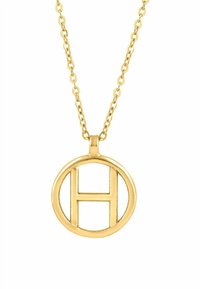 Auksinė vėrinys su apvaliu pakabuku, kuriame išpjauta raidė „H“. Grandinėlė turi vienodus žiedus ir blizgantį paviršių.