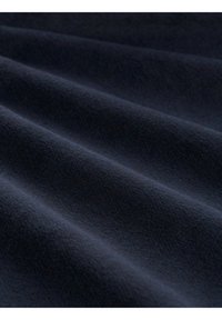 Tissu doux bleu foncé avec des plis subtils et une texture lisse montré en gros plan.
