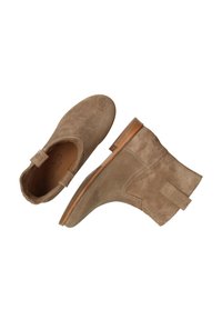 Botines de ante en color beige con un acabado liso, un tacón bajo en bloque y una lengüeta en la parte posterior. Presentan detalles de costura y una puntera redondeada.