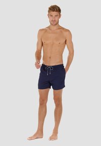 Marineblaue Badehosen mit elastischem Bund und Kordelzug, die ein klassisches Design und eine glatte Textur aufweisen, geeignet für Strandbekleidung.