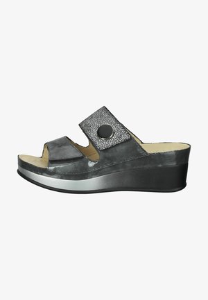 Sandalia wedge negra sin hebilla con punta abierta, con una tira texturizada que presenta un acento circular y un acabado suave y brillante.